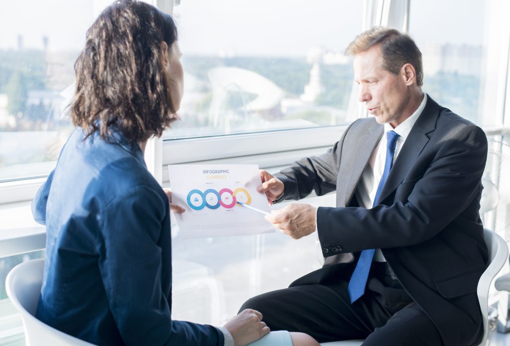 businessman explaining infographic elements sheet his female colleague How to Qualify Sales Leads Effectively