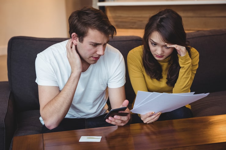 couple sitting sofa discussing with financial documents living room 107420 84892 Pay Per Appointment Model vs Retainer: 7 Key Differences You Must Know