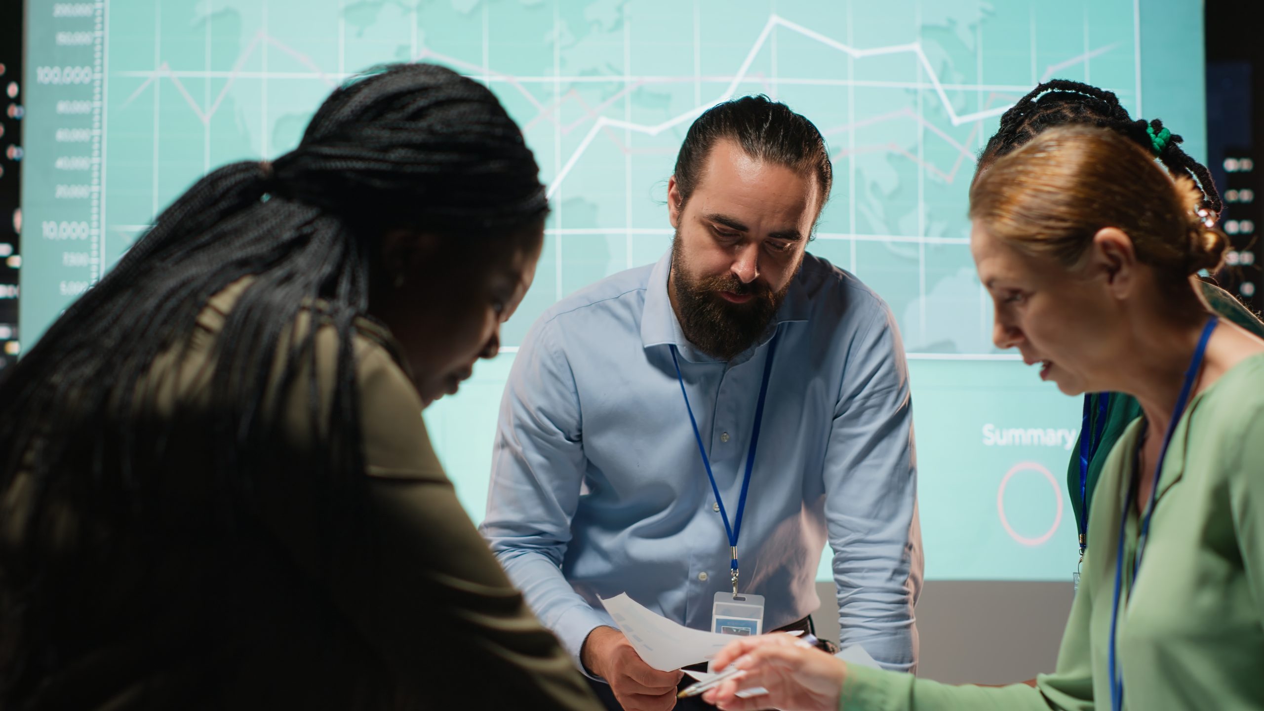 diverse group professionals review files performance metrics using projections budgeting scaled Home