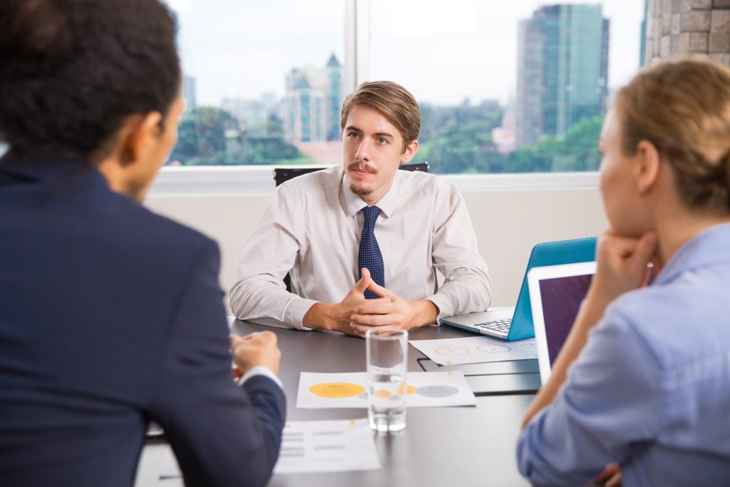 businessman sitting with laptop talking other colleagues Fractional Sales Leader: 7 Powerful Benefits for Growth