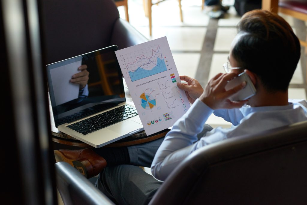 shoulder view man multitasking reviewing financial document having telephone chat Calculating Your Lead Generation ROI: 7 Smart Steps to Know What Works
